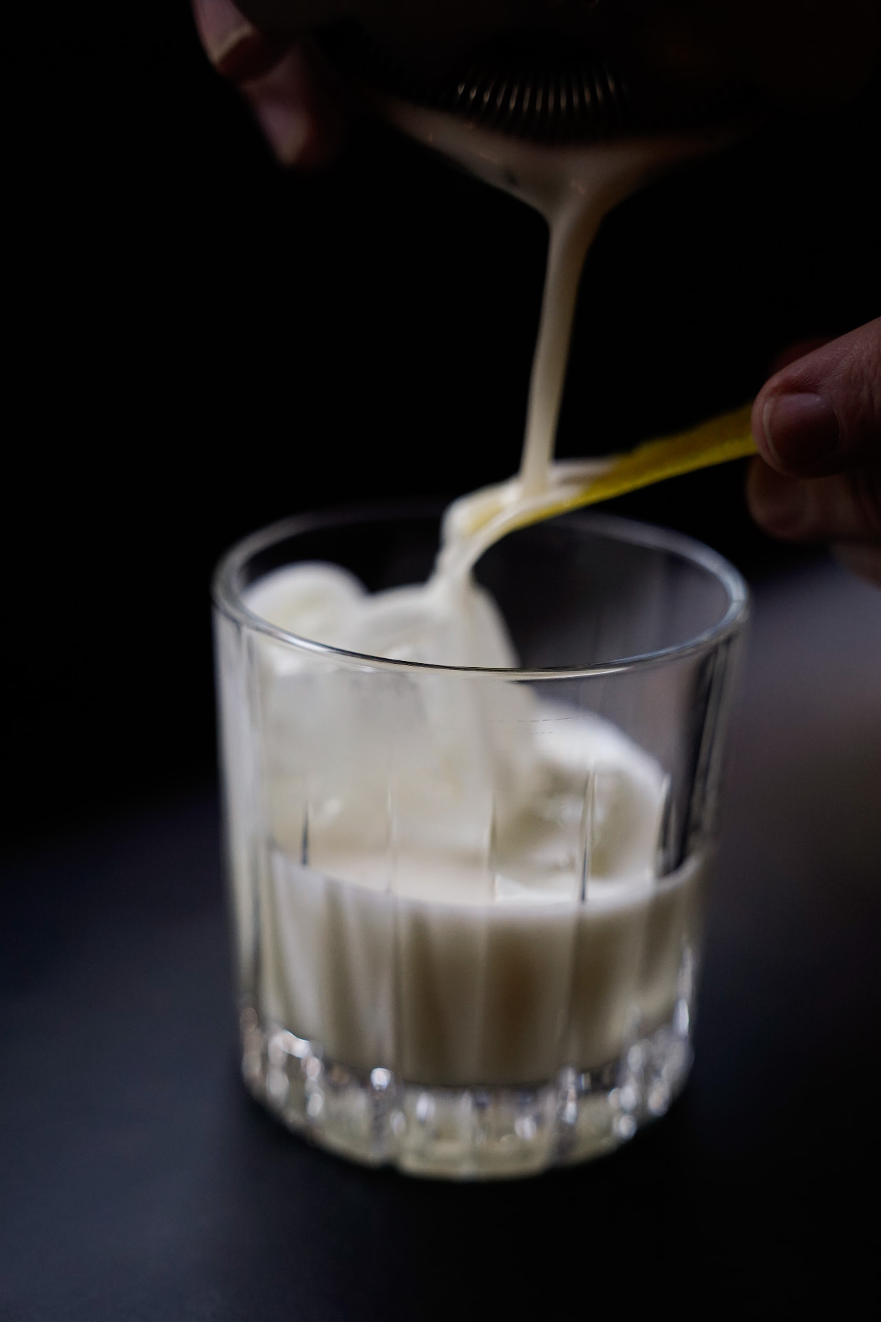 Creamy signature cocktail being poured into a rocks glass