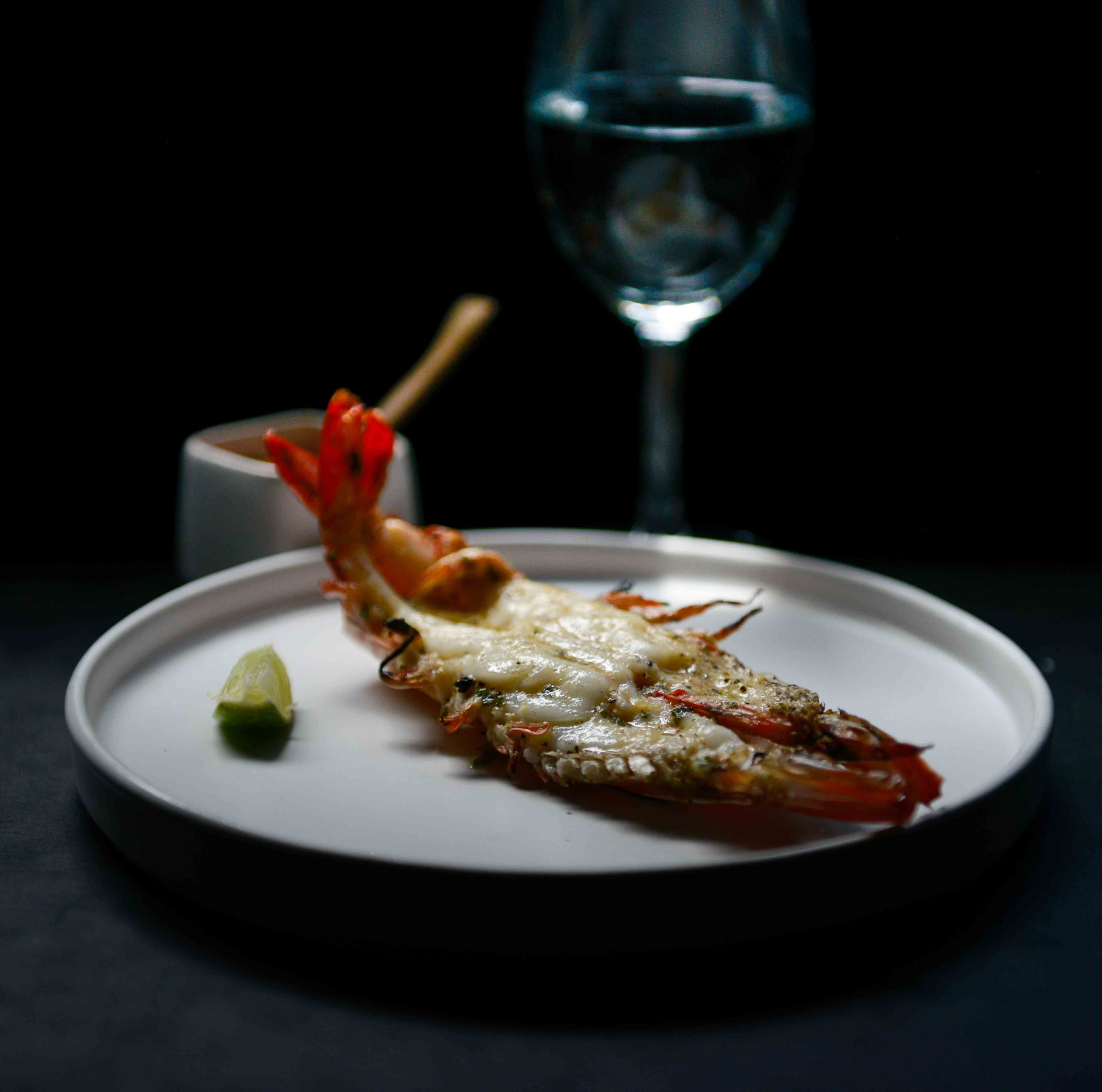 Grilled tiger prawn on a white plate with lime